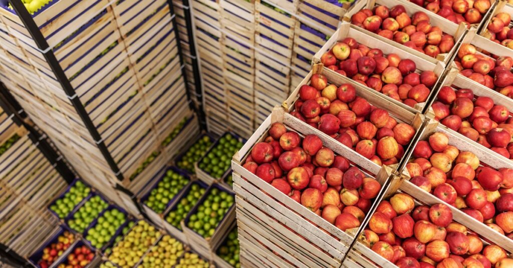 There are several stacks of boxes; the boxes at the top of the stacks each have different fruits and vegetables in them.