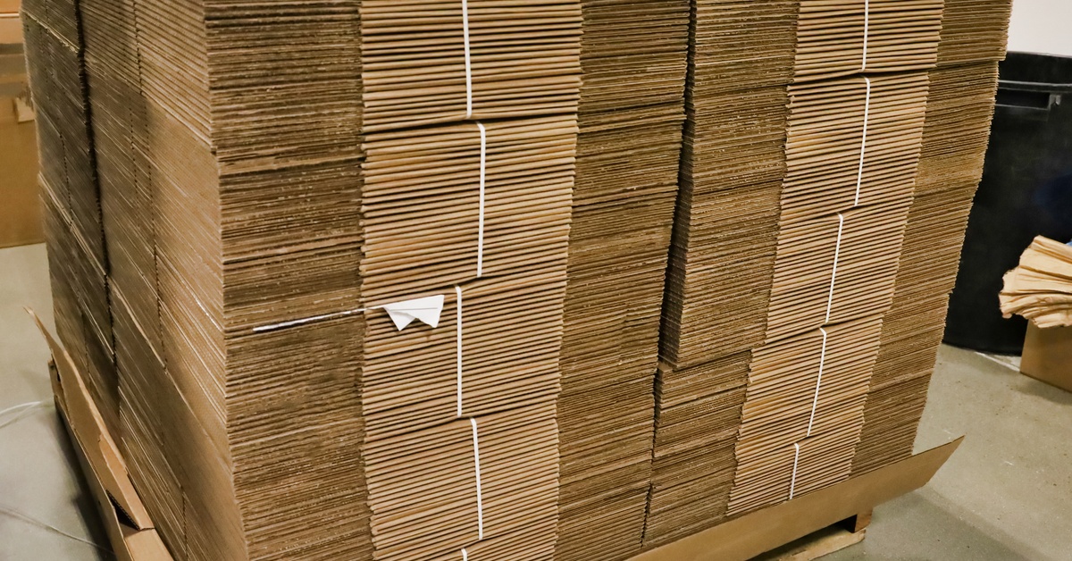 A stack of broken-down cardboard boxes. They are tied together with a length of plastic material.