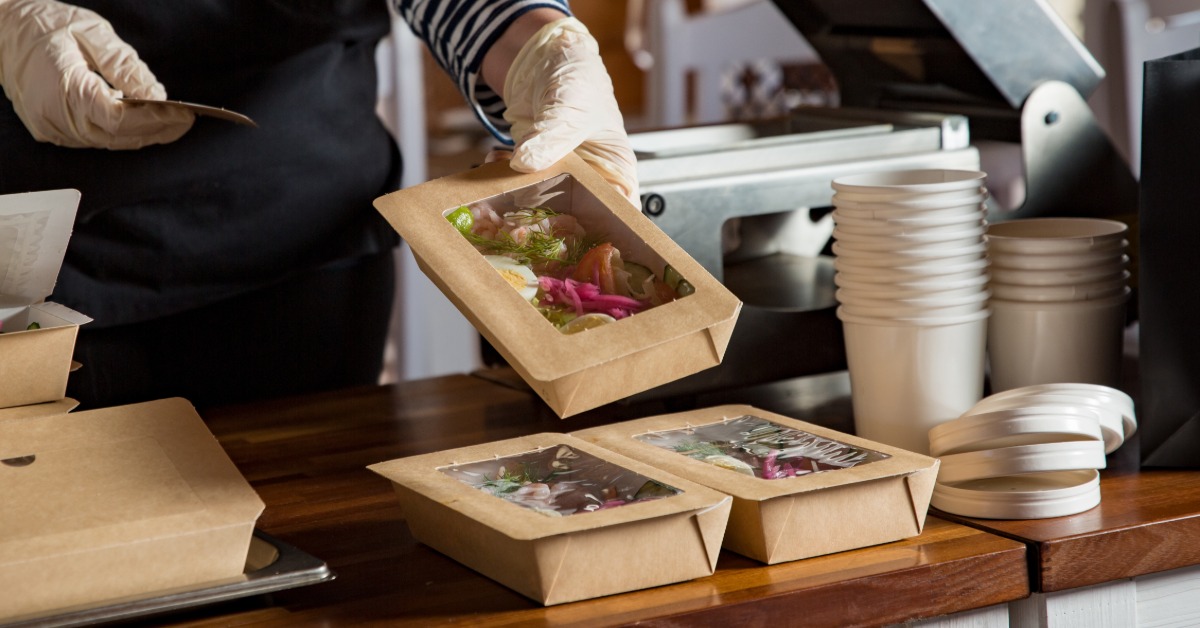 A person is holding a box of food. The box has a window, so that the viewer can see the food.