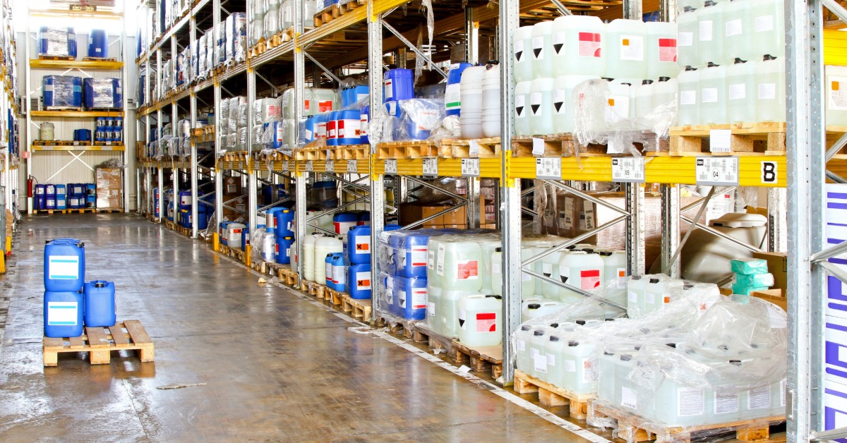 A warehouse with pallet racks. On the pallet racks are pallets filled with chemical materials.
