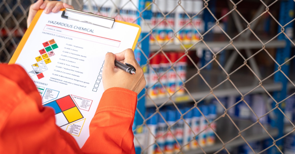 A person in an orange jumpsuit is holding a clipboard, and on that clipboard is a paper with check boxes.