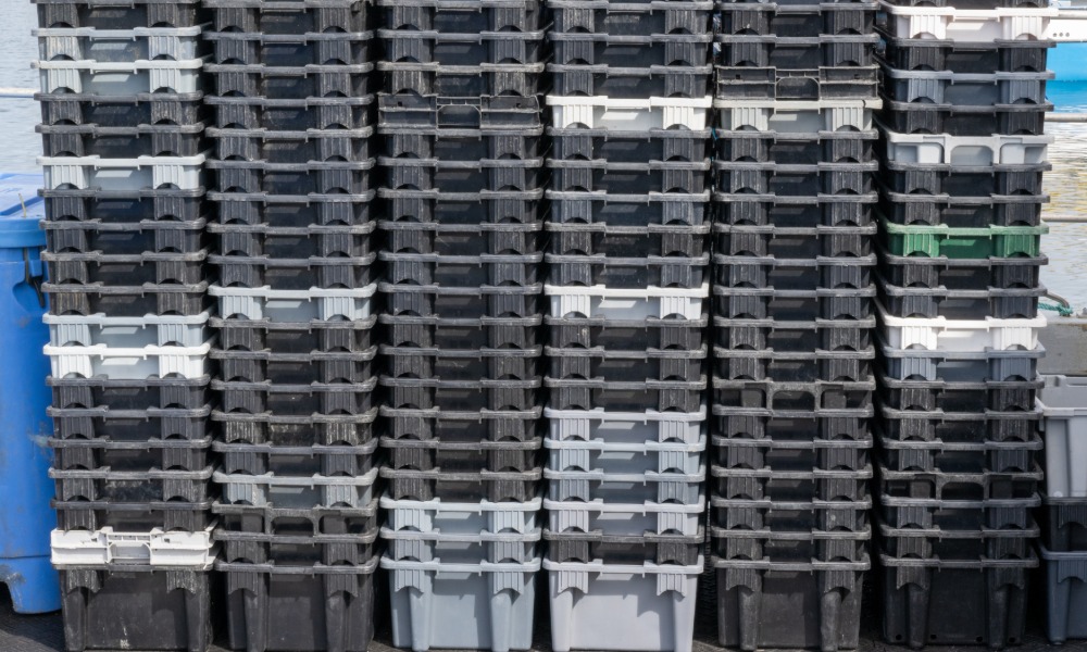 Several stacks of foot trays are pushed against a wall. The trays range in color from white to gray to black.