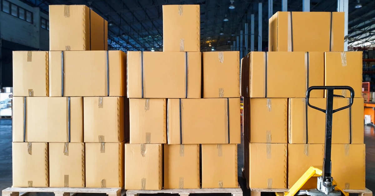 There are three pallets on the ground, and each one has a stack of cardboard boxes on them.