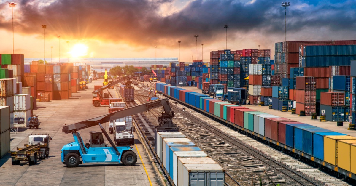 A port is filled with metal shipping containers. There are cranes there to move the containers onto boats.