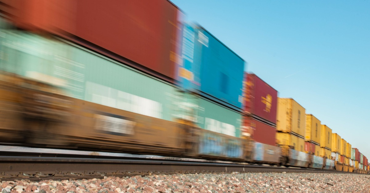 A train is passing by on tracks at a very high speed, as denoted by the blurring effect on the train cars.